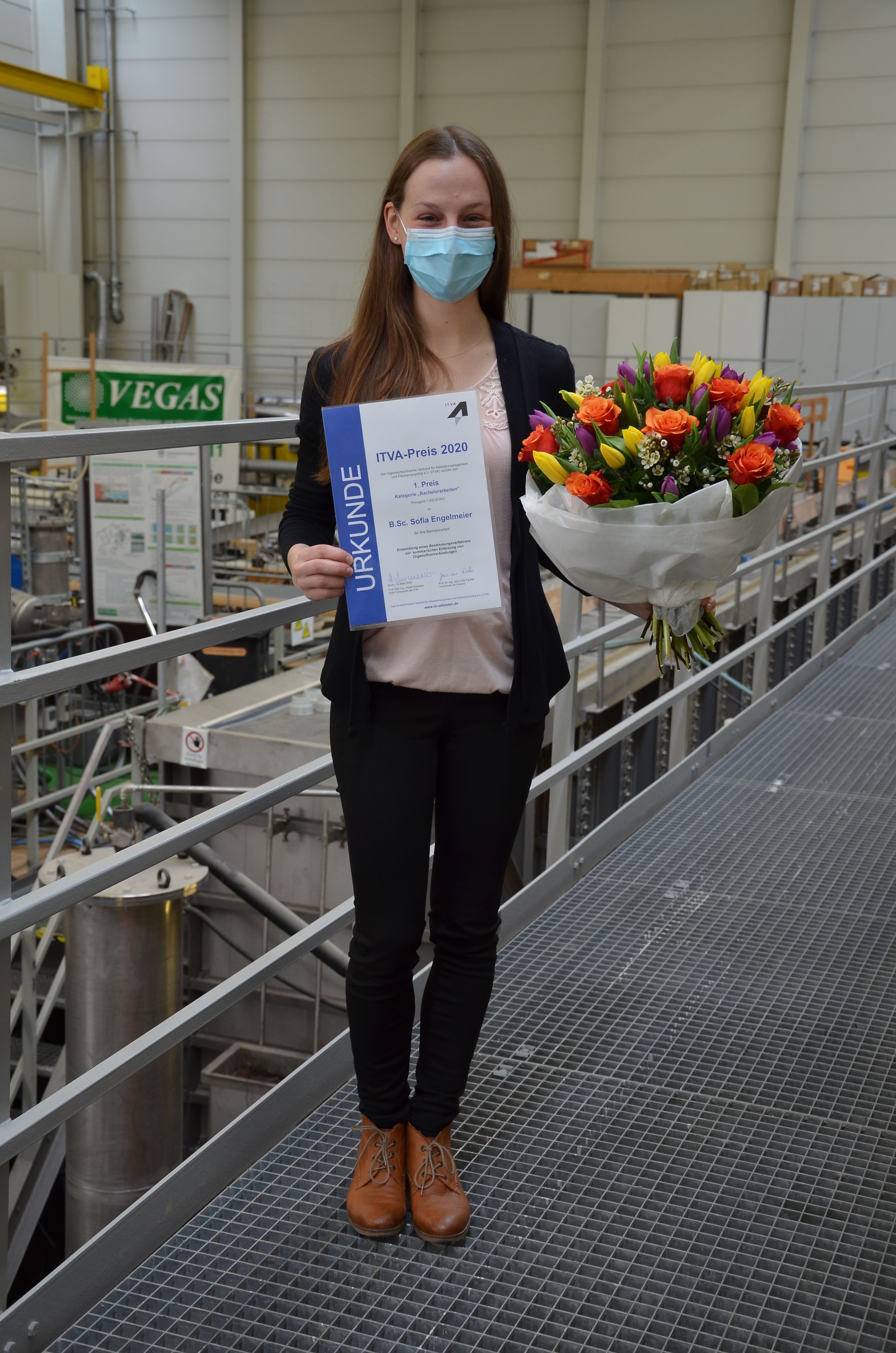 Sofia Engelmeier hält ihre Urkunde und einen Blumenstrauß in der Hand. Im Hintergrund ist die VEGAS-Halle zu sehen.