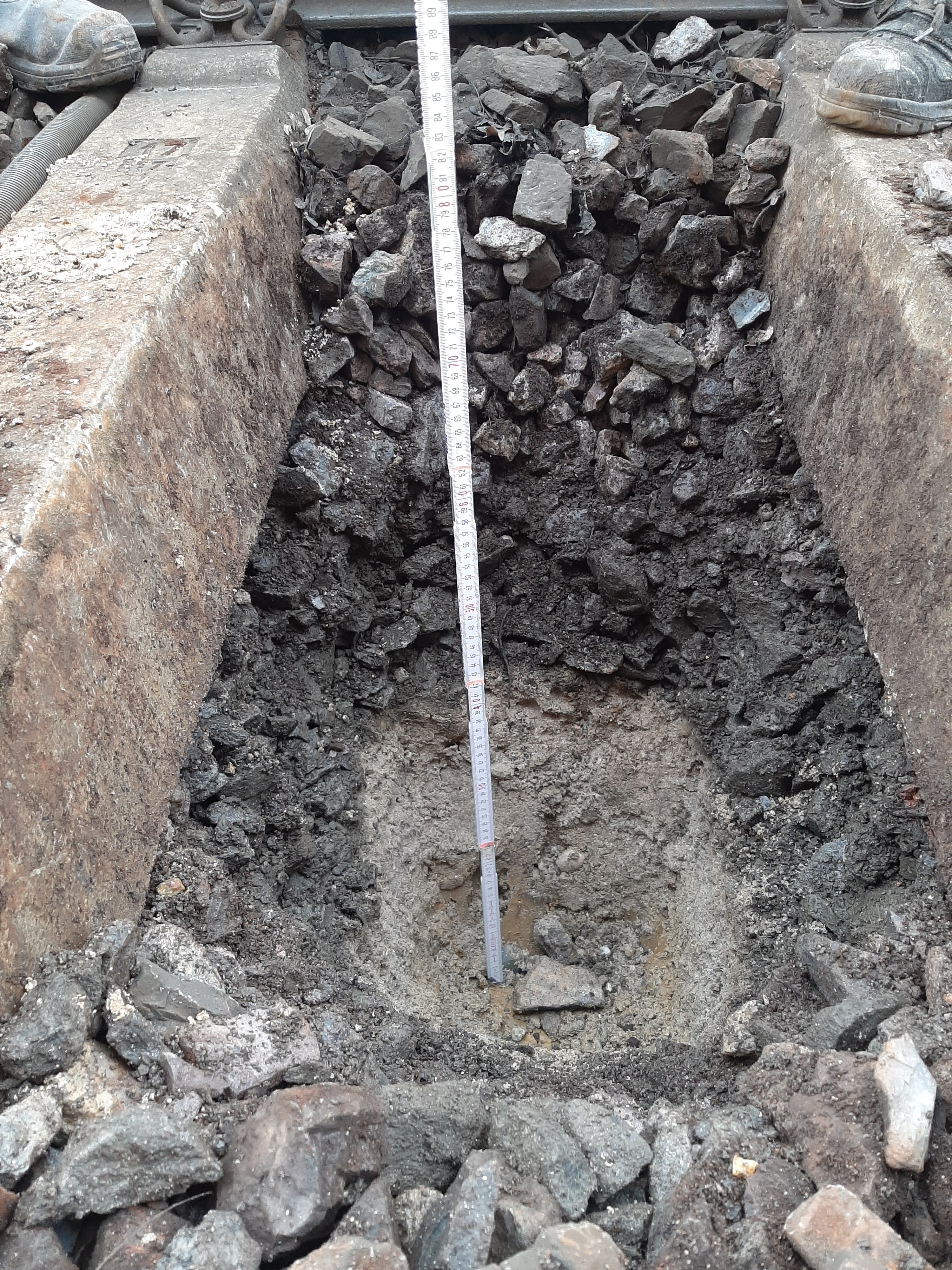 Gleisbett mit gegrabenen Loch: Probennahme aus verschiedenen Schichten des Gleismaterials